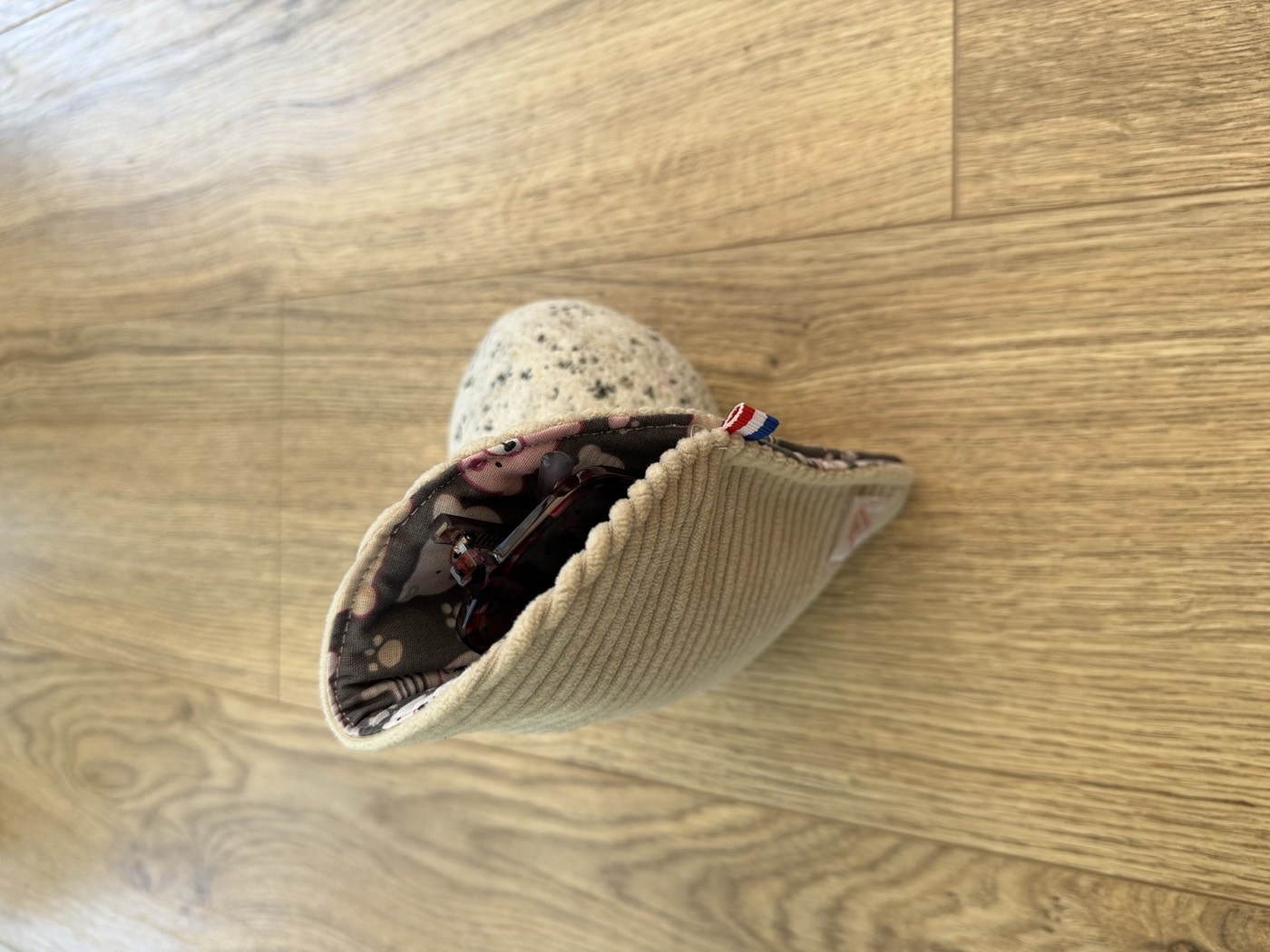 Étui à lunettes écru ouvert, doublure grise à oursons, avec une paire de lunettes
