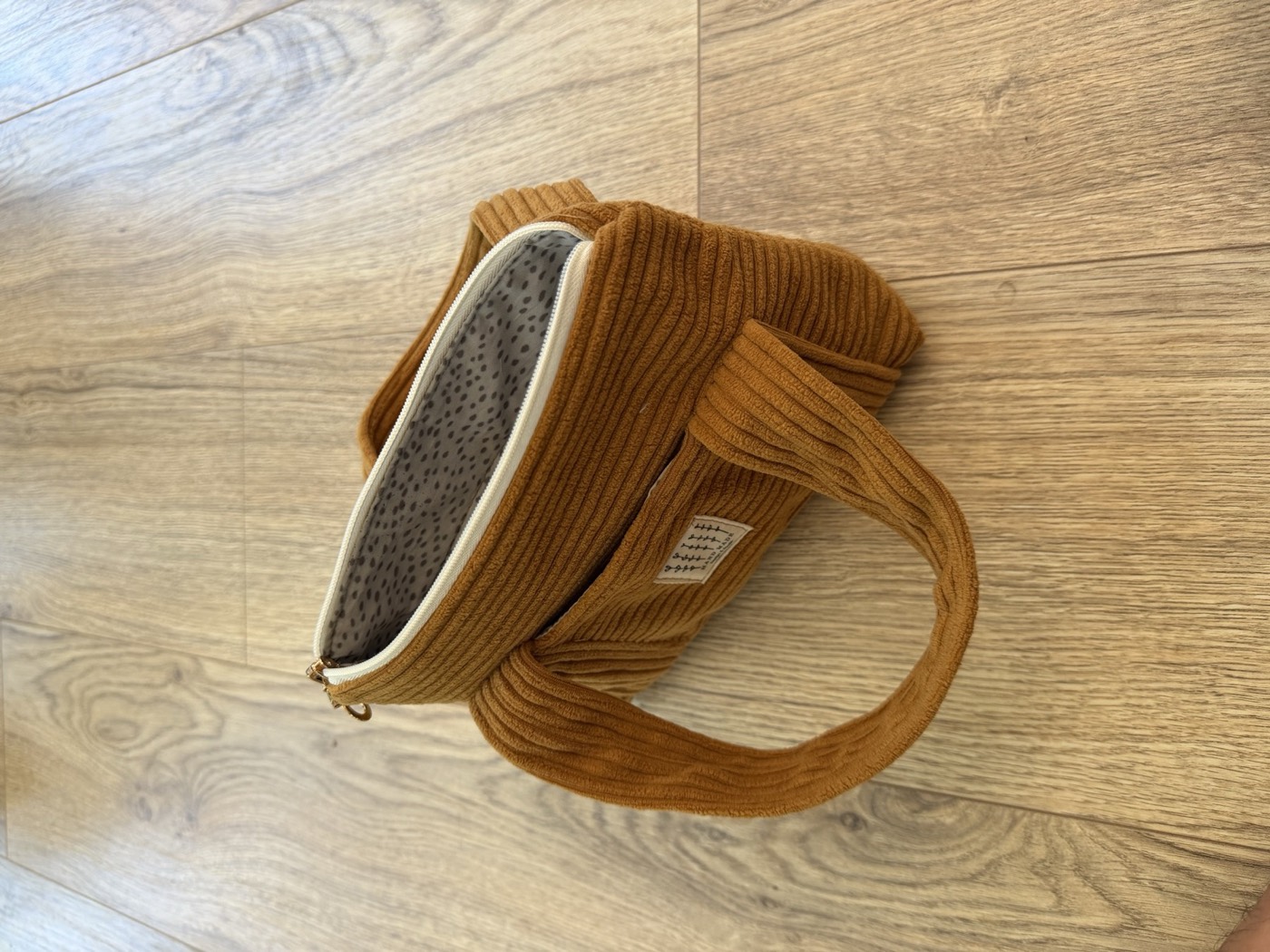 Petit sac à main camel entrouvert, fermeture zippée et doublure grise à pois