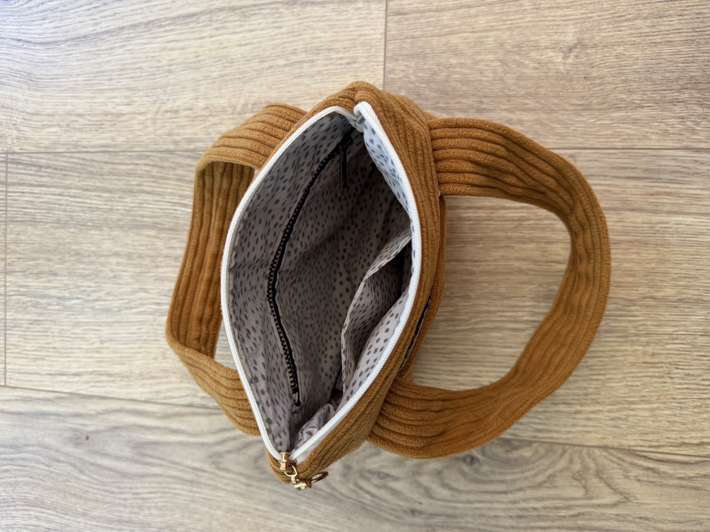 Intérieur du petit sac à main camel, doublure grise à pois et poche intérieure zippée