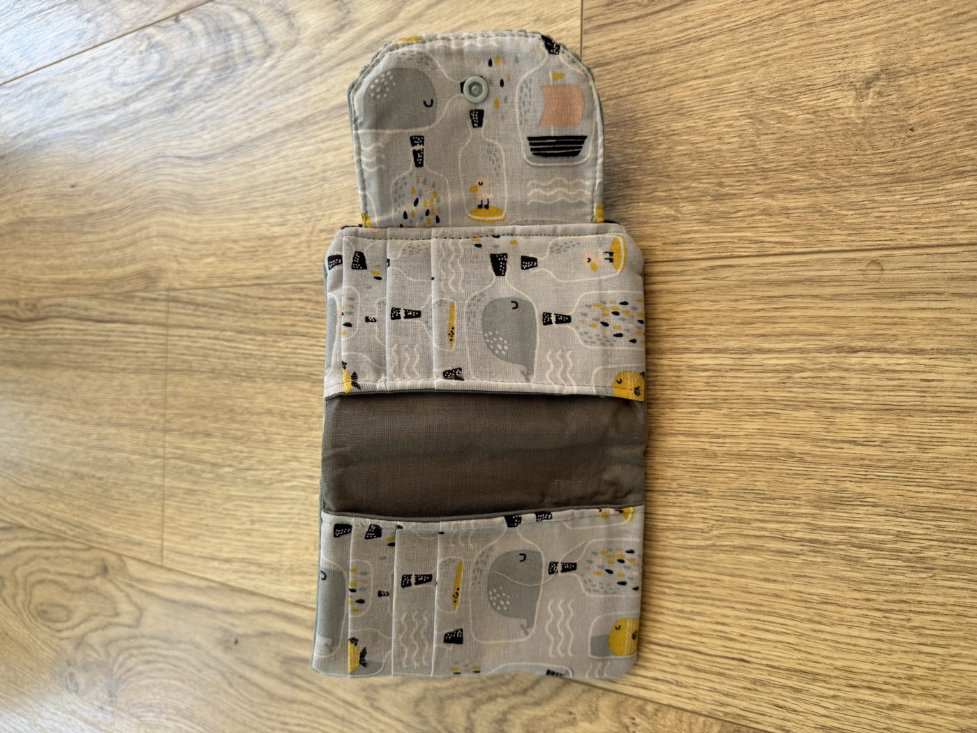 Porte-monnaie gris ouvert à plat, emplacements cartes et doublure à motifs marins